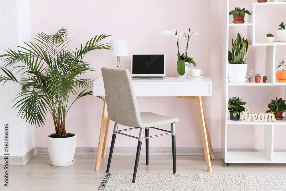 Stylish interior of room with green houseplants and workplace