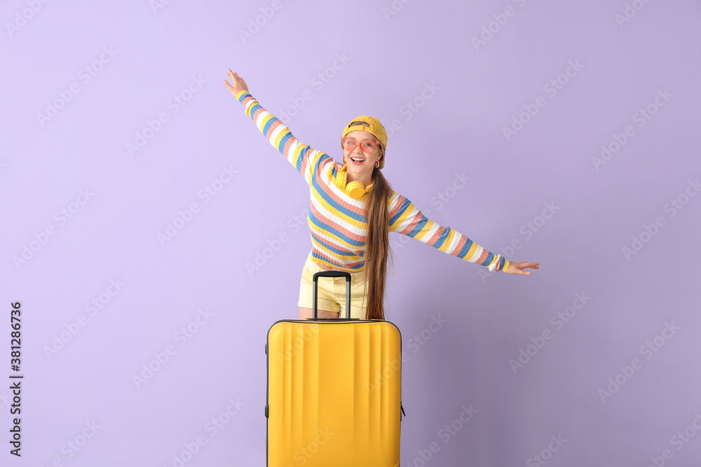 Young woman with suitcase near color wall. Travel concept