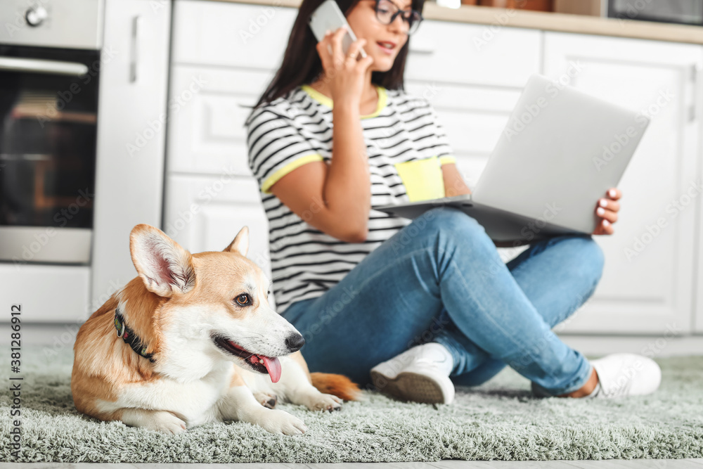 Woman with cute corgi dog in kitchen at home