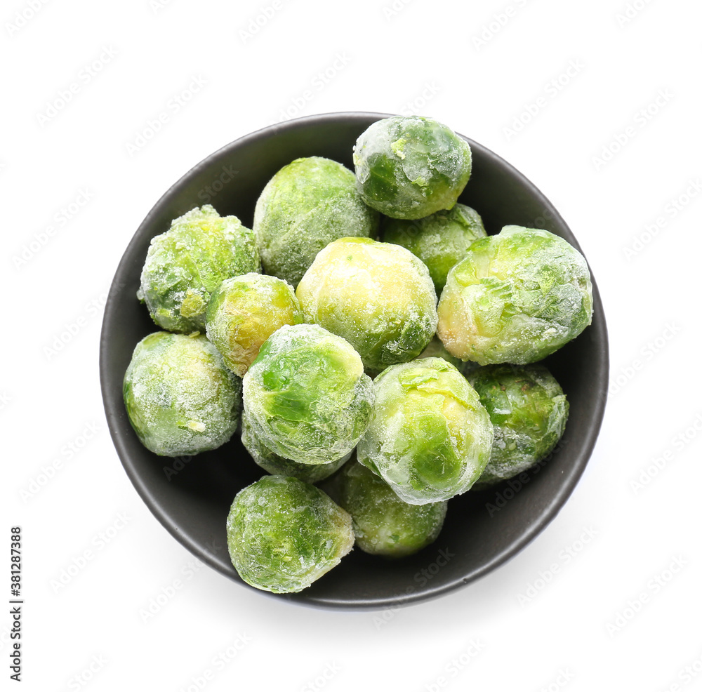 Bowl with frozen Brussels sprouts on white background