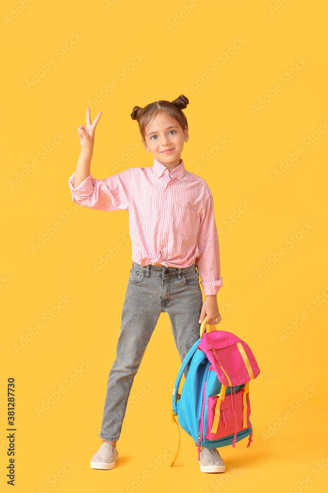 Little schoolgirl with backpack on color background