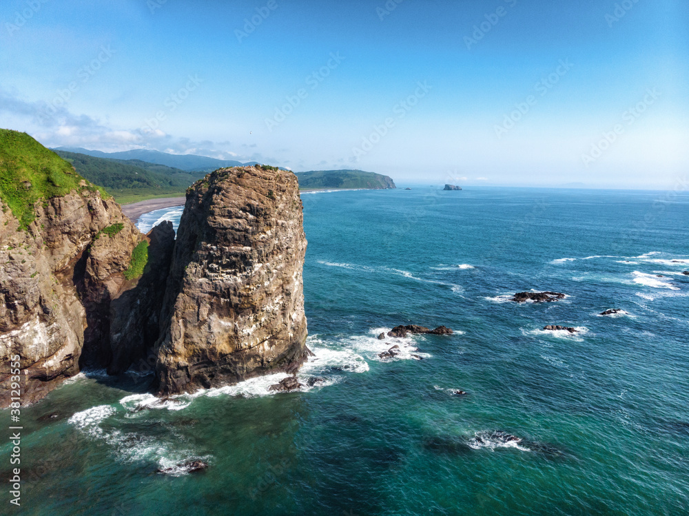 Green beautiful rocks of Kamchatka against the background of the bright blue sky.