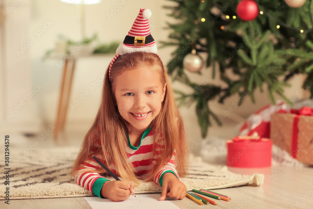 Cute little girl writing letter to Santa Claus on Christmas eve at home