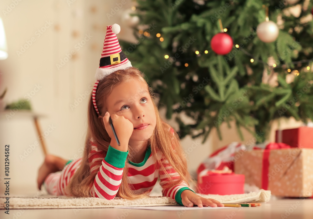 Cute little girl writing letter to Santa Claus on Christmas eve at home