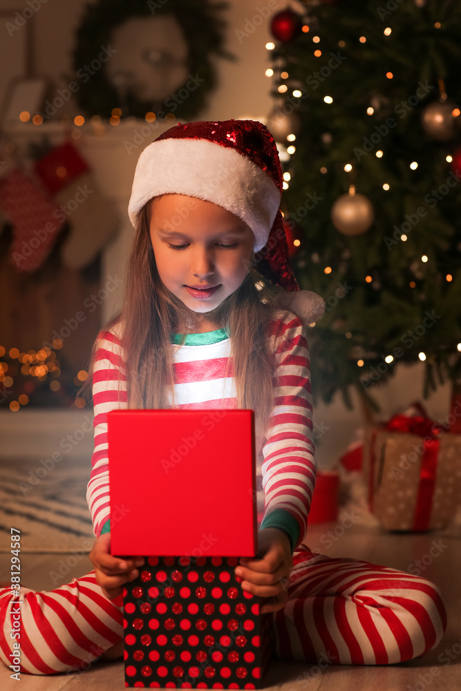 Cute little girl with Christmas gift at home in evening