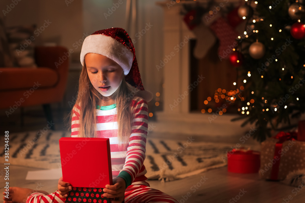 Cute little girl with Christmas gift at home in evening