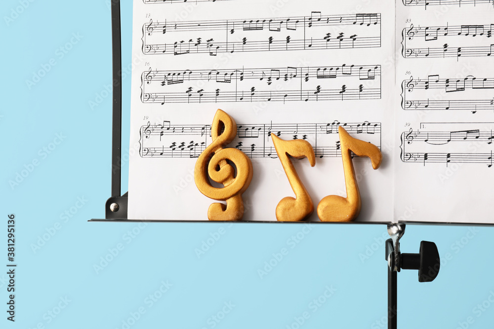 Music sheets with notes on stand against color background