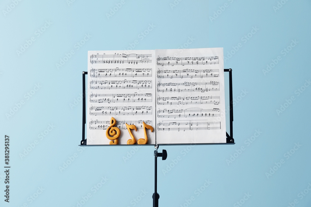 Music sheets with notes on stand against color background