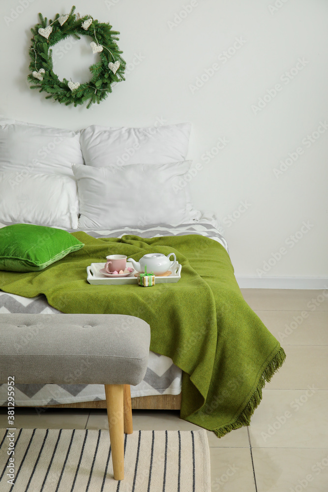 Beautiful Christmas wreath hanging on wall in interior of bedroom