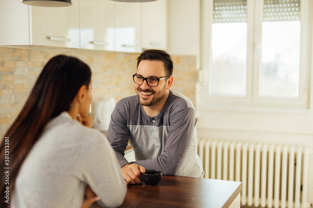 Home portrait of a cute couple in pajamas at kitchen table.