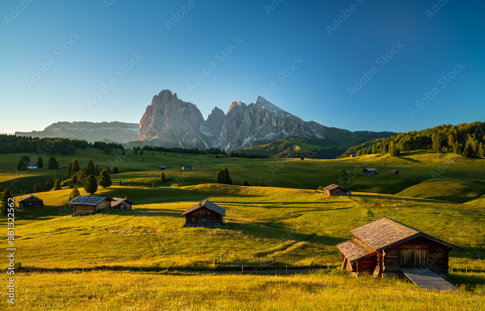 Chalets at Seiser Alm, high altitude meadow with Langkofel mountain in background at sunrise, Dolomi