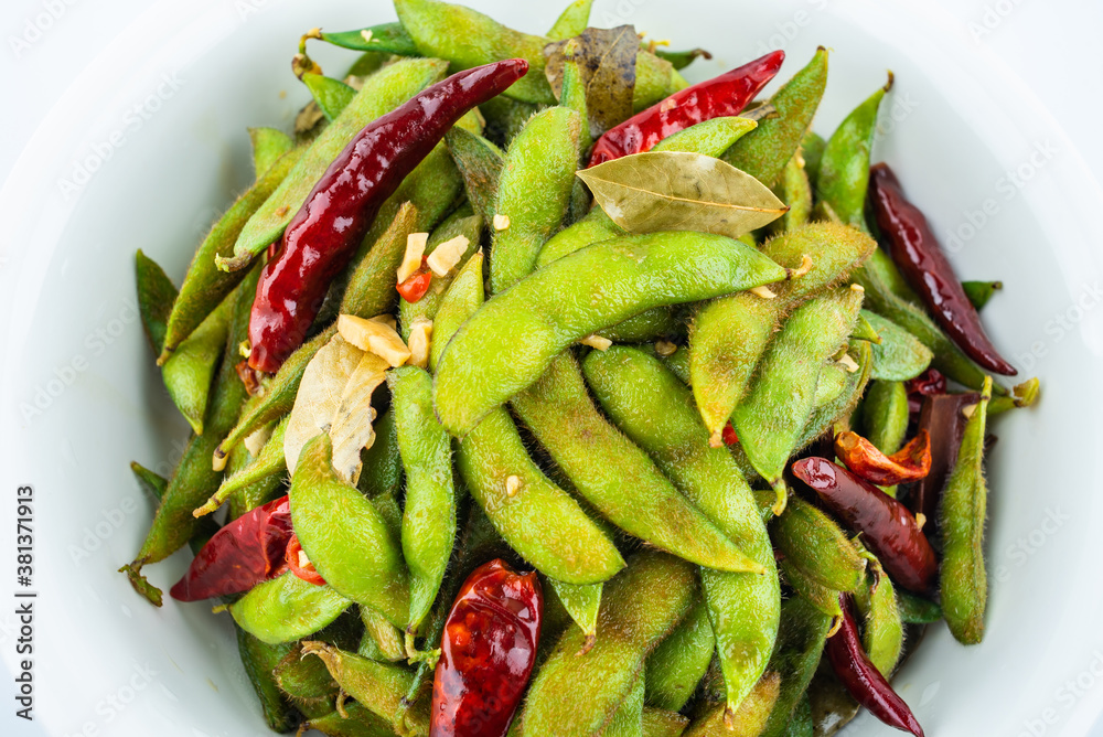 A pot of delicious spicy edamame on white background