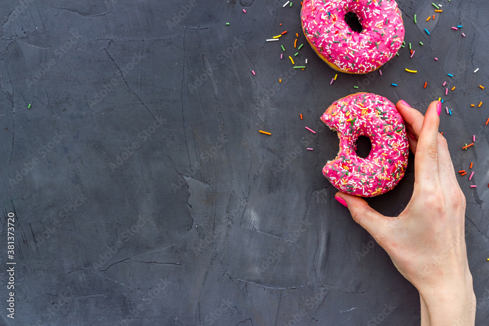 Hand holding glazed donut swith sprinkles, above view