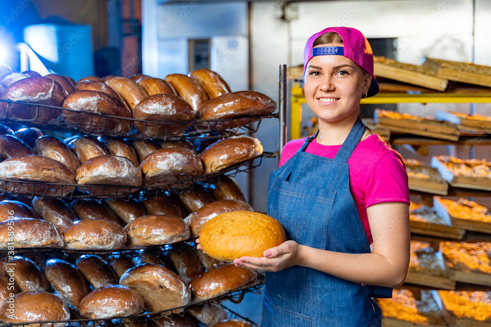 Bread in the hands of a baker on the background of an industrial oven. Industrial bread production