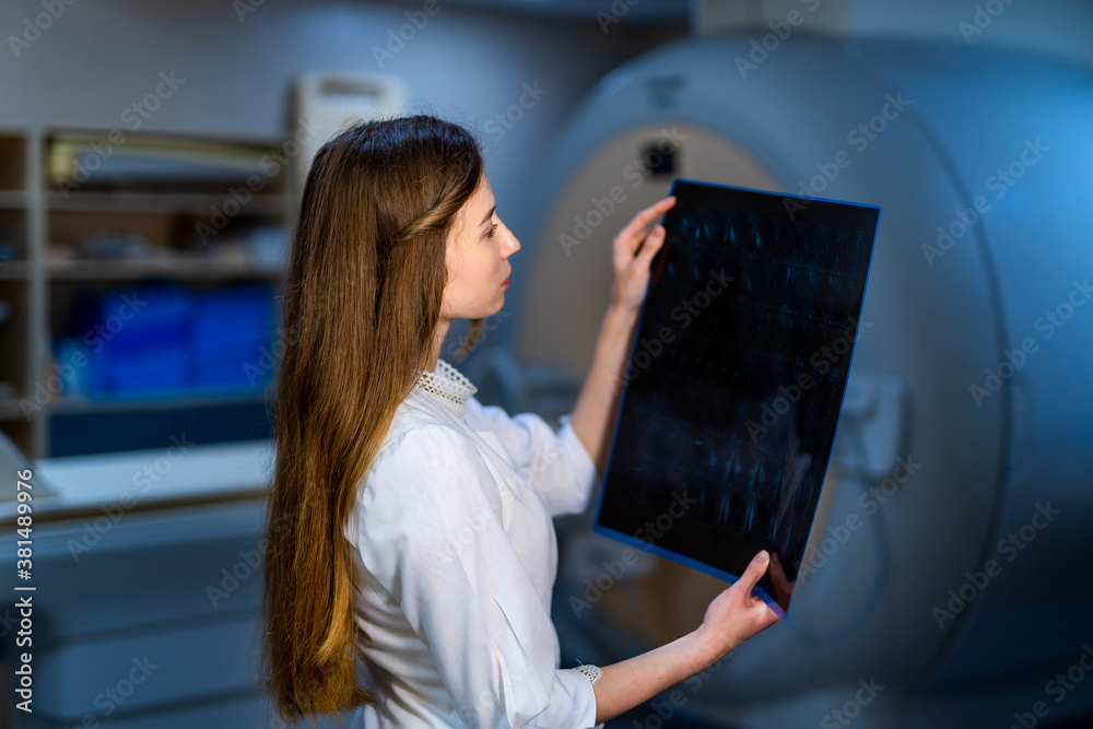 Hospital doctor holding patients x-ray film. Modern MRI machine background. Healthcare, roentgen, p