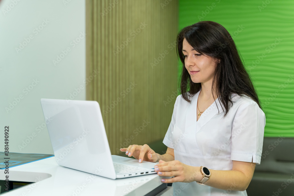 Female doctor at work uses laptop. Competent medic prescribes medicine.