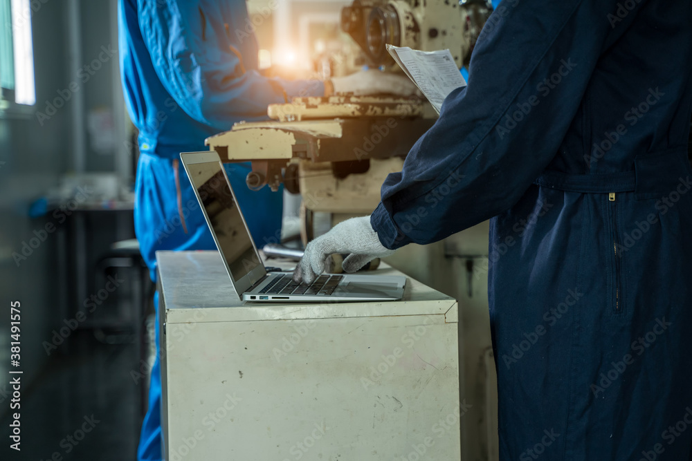 Industrial workers with a laptop working on the background of the equipment at metal industrial manu