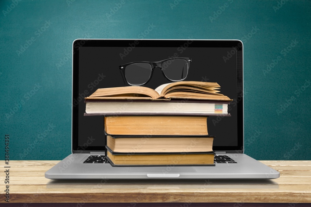 Stack of books with a modern laptop on the table