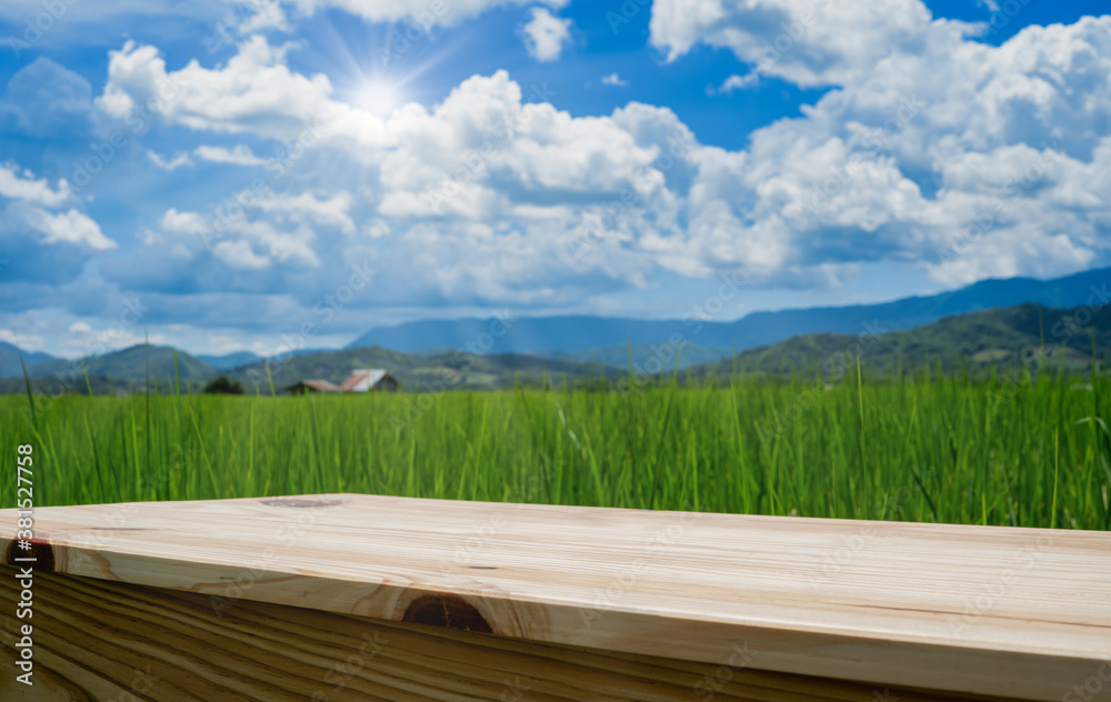 wooden table on agricultural rice field beside mountain with blue sky for use show product with copy