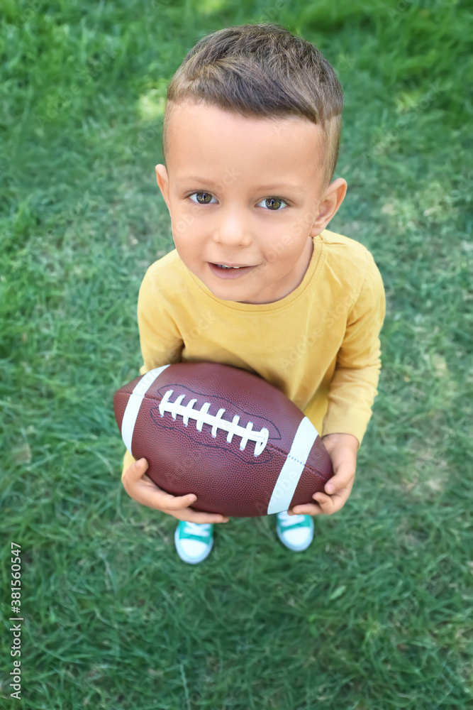 Little boy playing American football outdoors