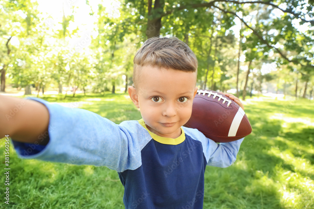 Little boy with rugby ball taking selfie outdoors