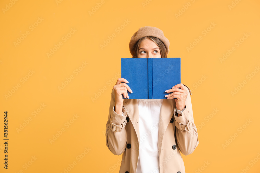 Beautiful young woman with book on color background