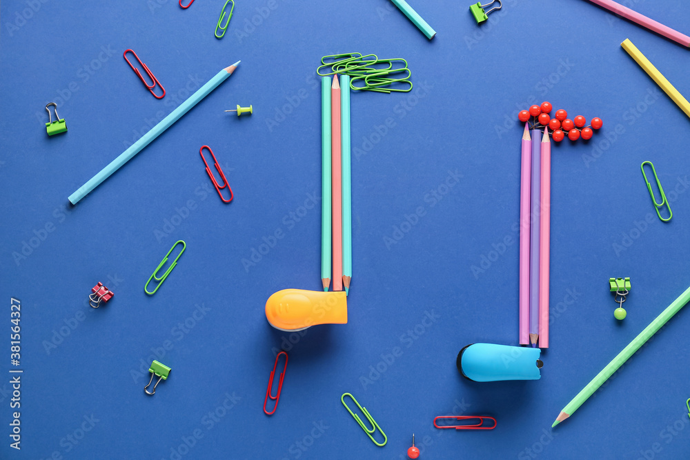 Music notes made of stationery on color background