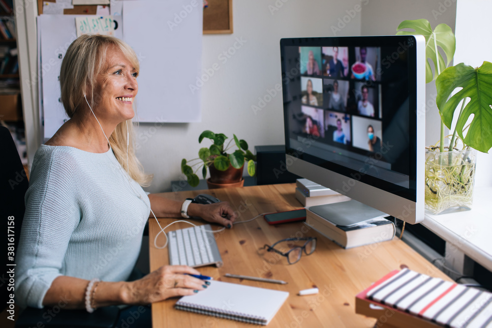 Smiling mature woman having video call via computer in the home office. Online team meeting video co