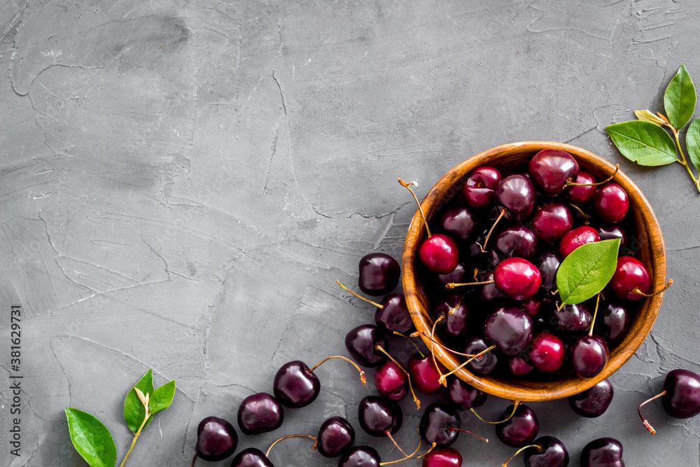 Red cherries with leaves in wooden bowl. Layout, berries background