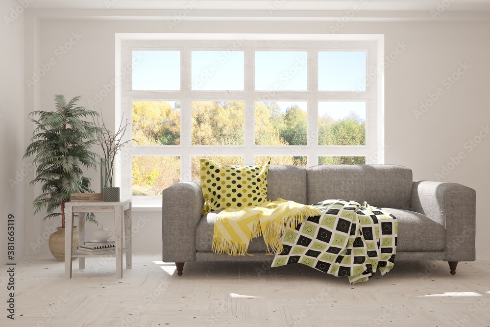 Stylish room in white color with sofa and autumn landscape in window. Scandinavian interior design. 