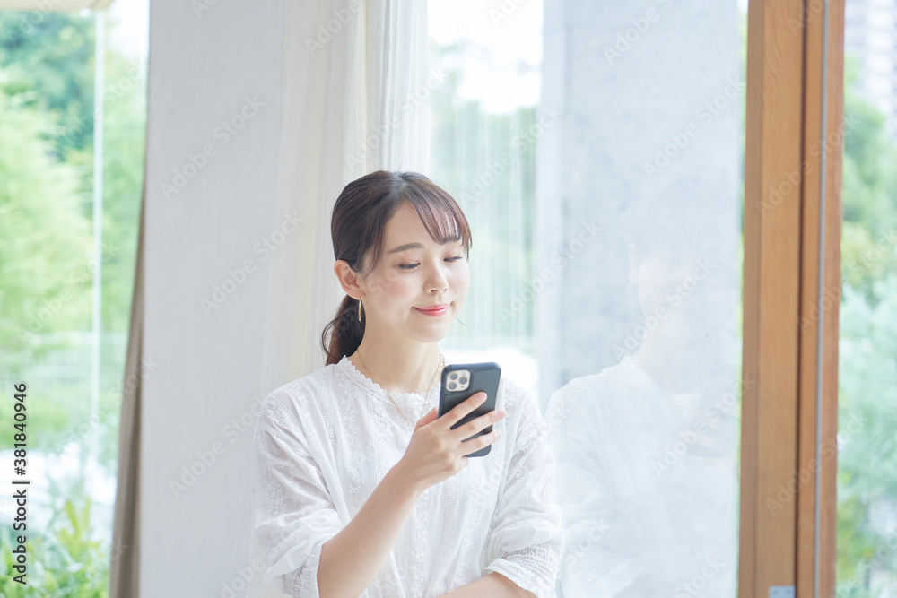 部屋でスマートフォンを使う女性