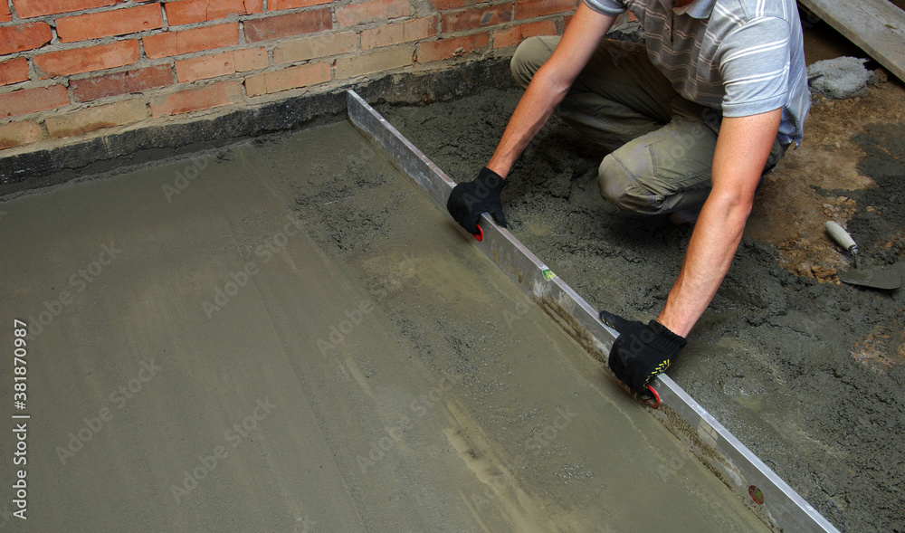 worker screeding indoor cement floor with screed