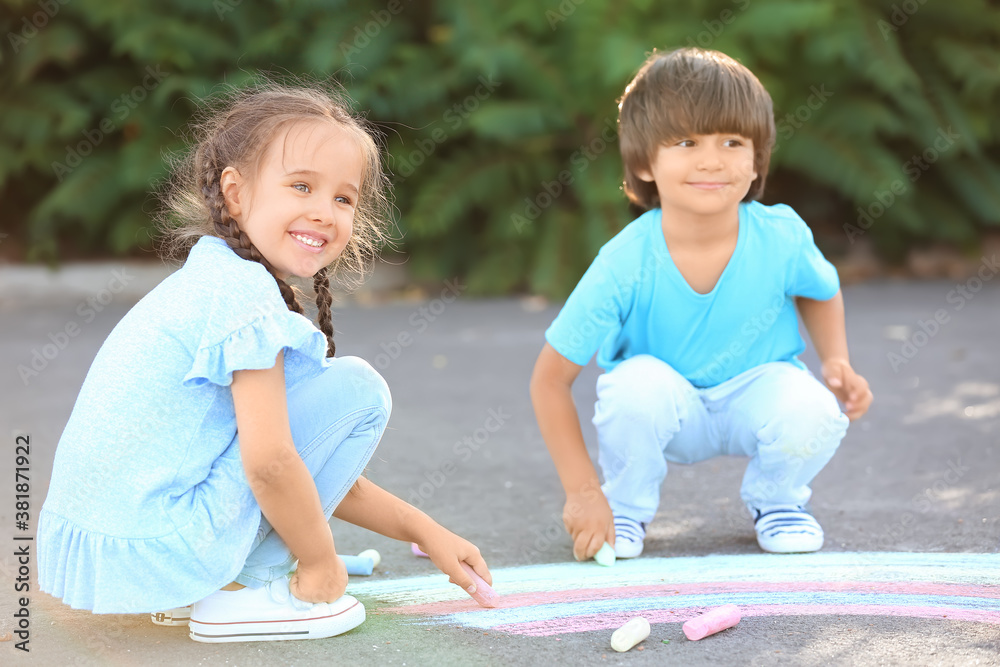 Little children drawing with chalk on asphalt