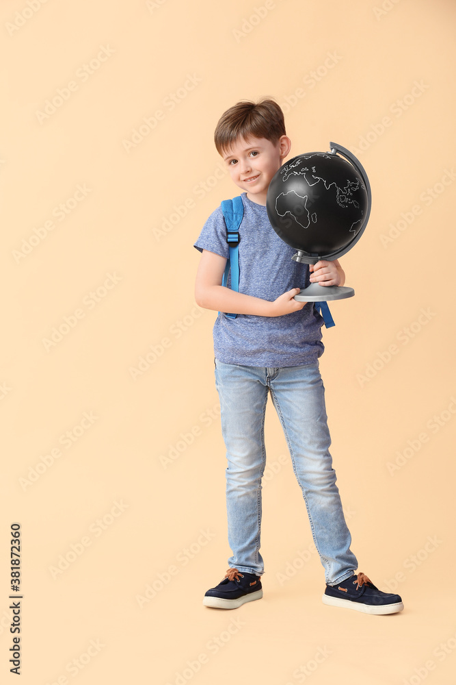 Little schoolboy with globe on color background