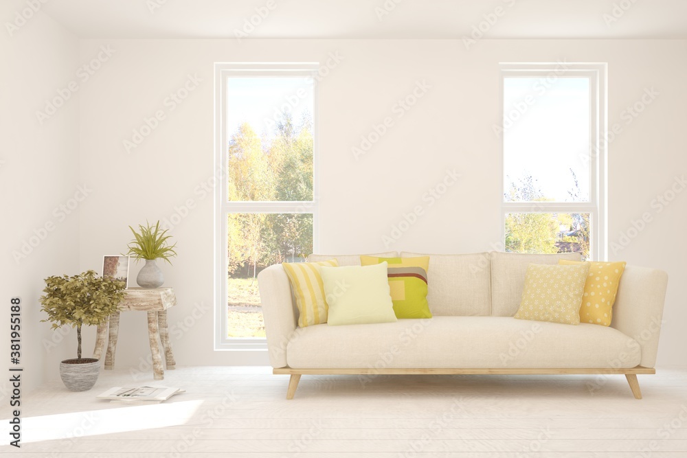 Stylish room in white color with sofa and autumn landscape in window. Scandinavian interior design. 