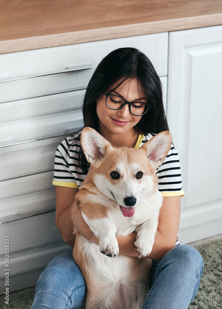 Woman with cute corgi dog in kitchen at home