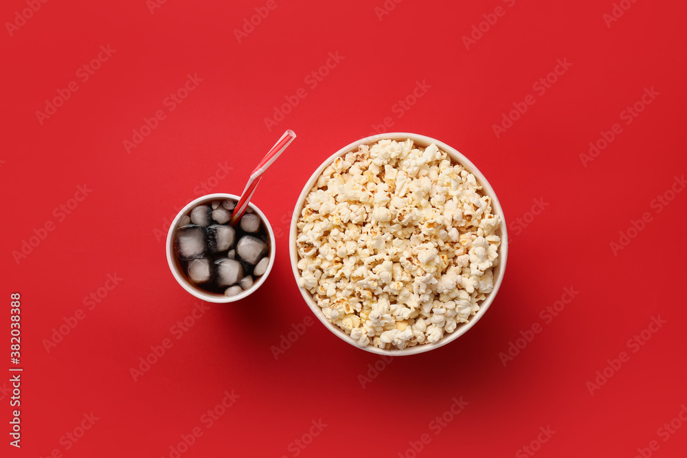 Tasty popcorn and cola on color background