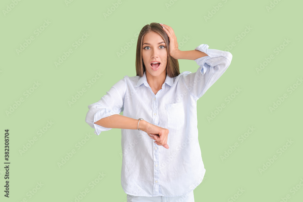 Shocked young woman with wristwatch on color background