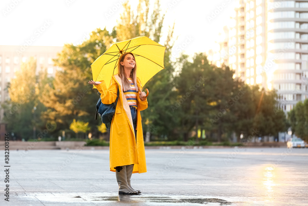 美丽的年轻女子，带着雨伞，在户外穿着雨衣