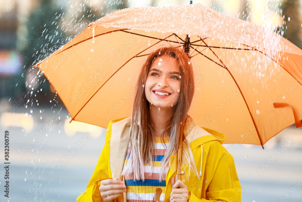 美丽的年轻女子，带着雨伞，在户外穿着雨衣