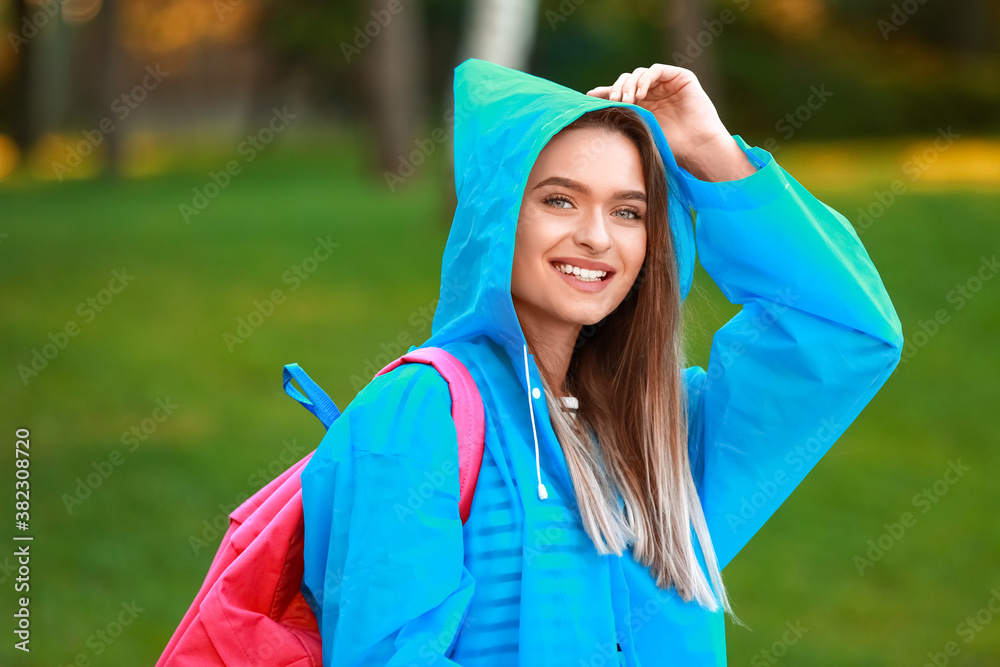 Beautiful young woman wearing raincoat in park