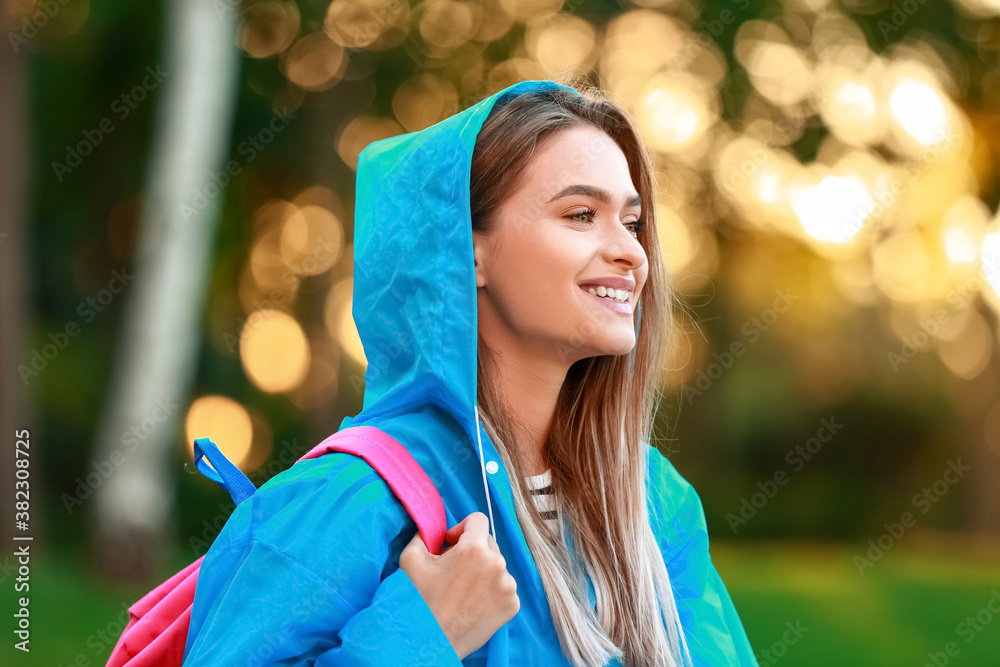 Beautiful young woman wearing raincoat in park