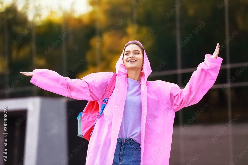 Beautiful young woman wearing raincoat outdoors