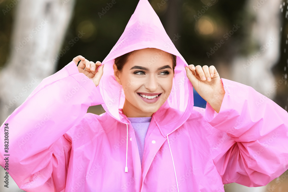 Beautiful young woman wearing raincoat outdoors