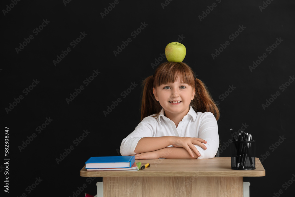 黑暗背景下，一个小学生坐在学校的桌子旁