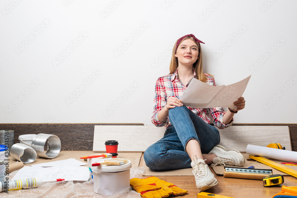 Smiling girl sitting on floor with blueprint