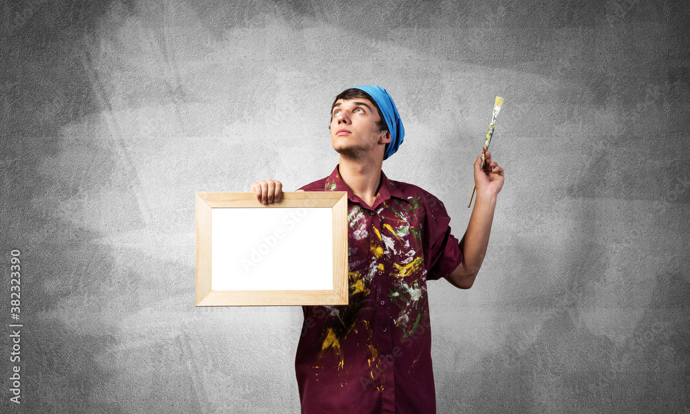 Young handsome painter artist holding paintbrush