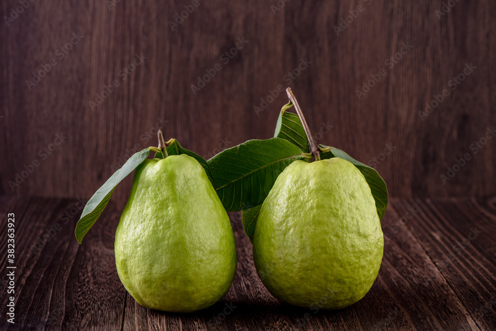 Delicious beautiful Guava set with fresh leaves isolated on wooden table background, close up.