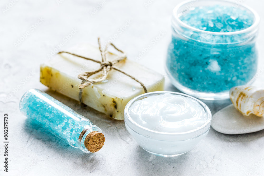 blue bath salt, body cream and shells for spa on white table background