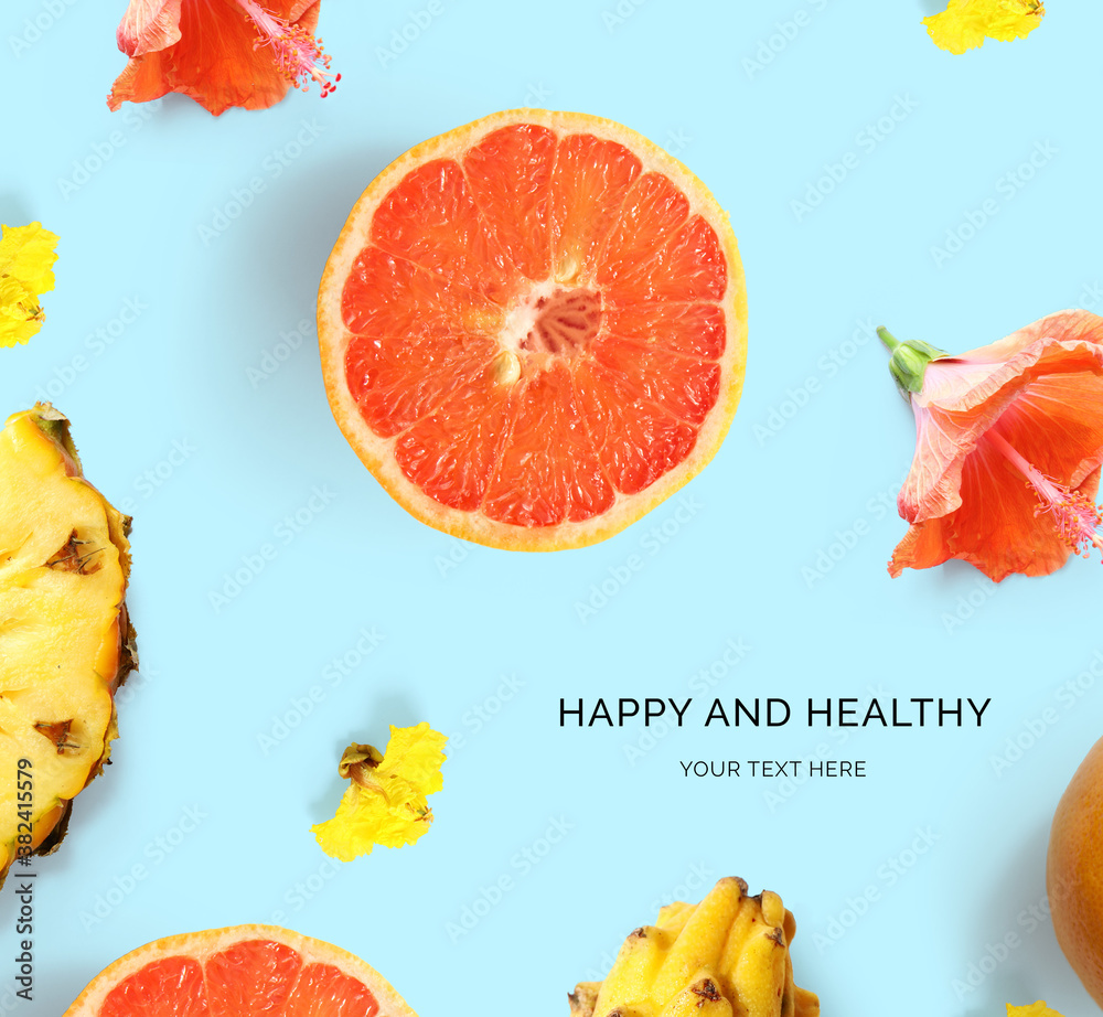 Creative layout made of grapefruit, flowers and pineapple on the blue background. Flat lay. Food con